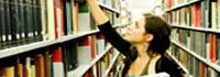 Eine Frau zieht ein Buch aus einem Bücherregal, Copyright: iStock