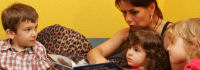 Erzieherin mit Kindern und Bilderbuch