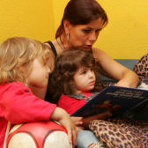Erzieherin mit Kindern beim Betrachten eines Kinderbuches